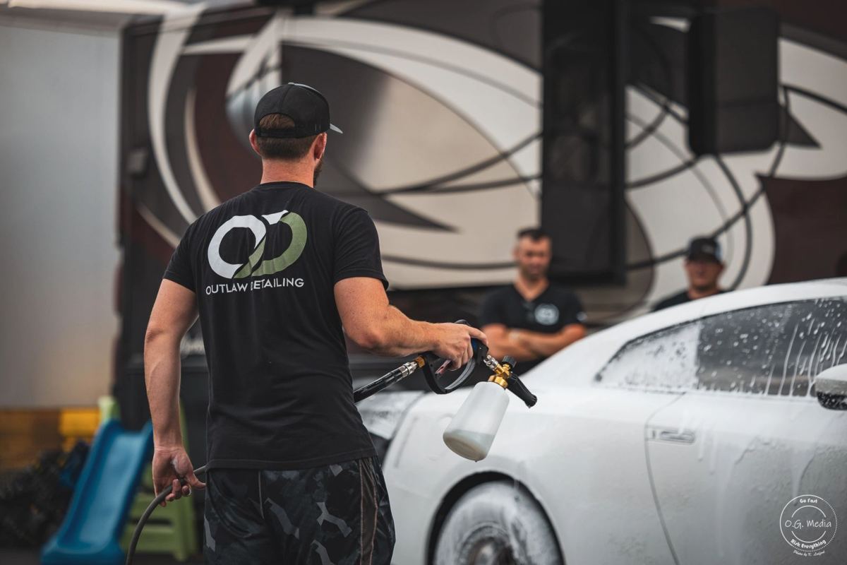 Outlaw Detailing technician foam washing a white sports car