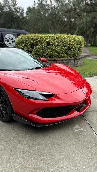 Front three-quarter view of a red Ferrari 296 with reflective paint