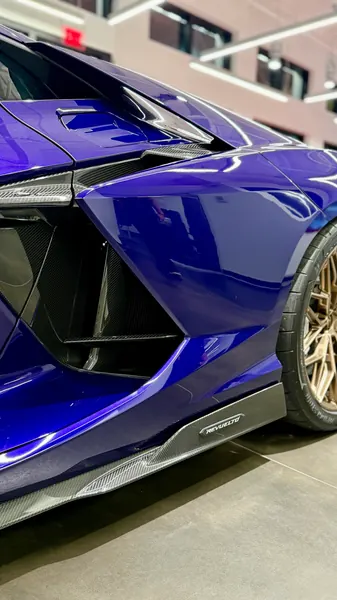 Close-up of the polished purple side intake and carbon sill of a Lamborghini Revuelto