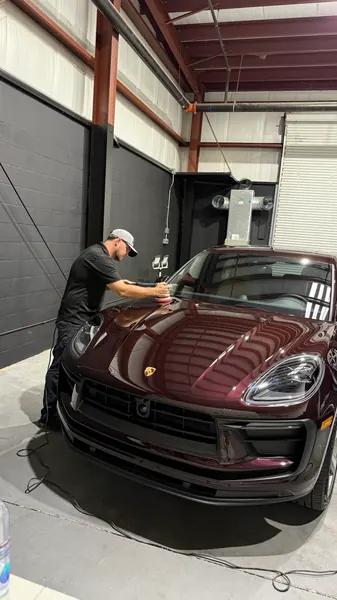 Detailer working on a burgundy Porsche SUV