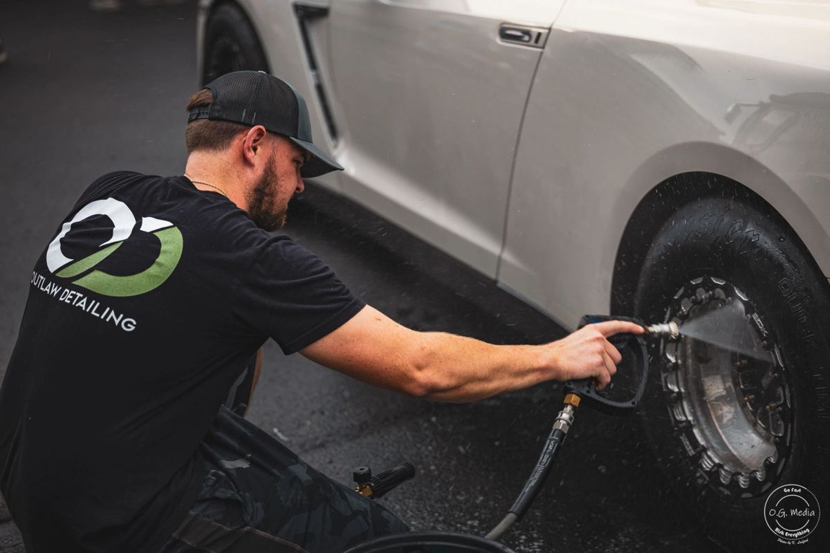 Detailer cleaning a wheel and tire with a brush